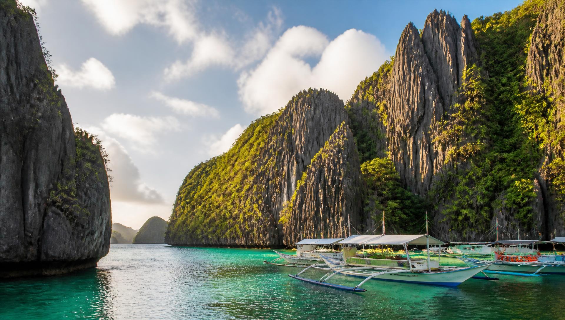 Limestone cliffs and outrigger boats in a turquoise lagoon in El Nido, Palawan